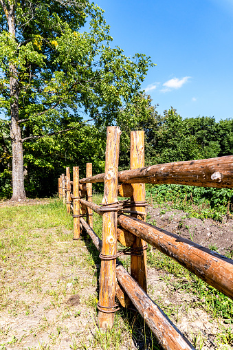 Fence made of natural wooden poles at the countryside in summer