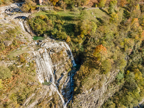 Aerial view of fortified bridge spanning waterfall in forest