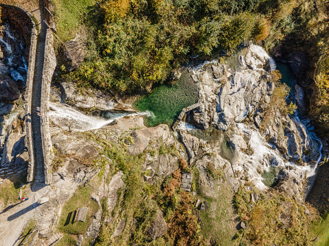 Bird's-eye view of fortified bridge spanning waterfall in forest