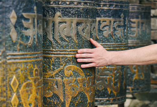 Man's hand spins Nepalese prayer wheels, close-up view