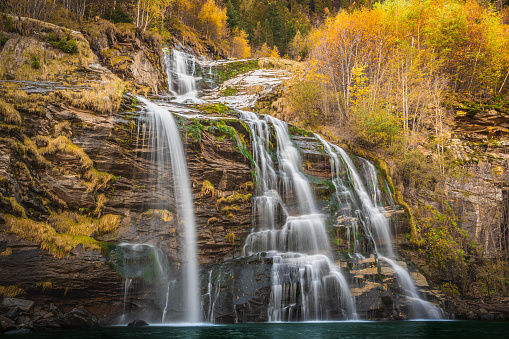 Waterfall cascades down cliff into pool in autumn