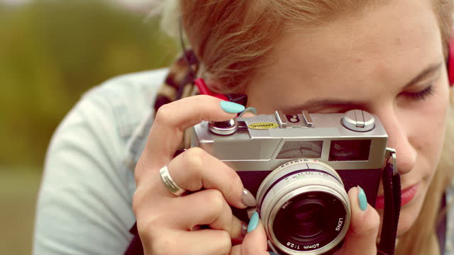Young woman taking photo of nature with retro camera
