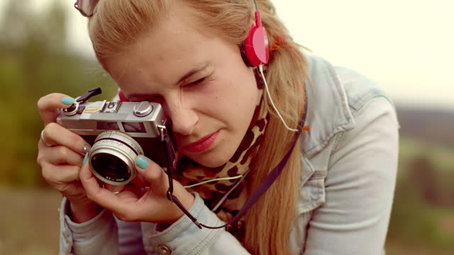 Young woman taking photo pictures of nature with retro camera