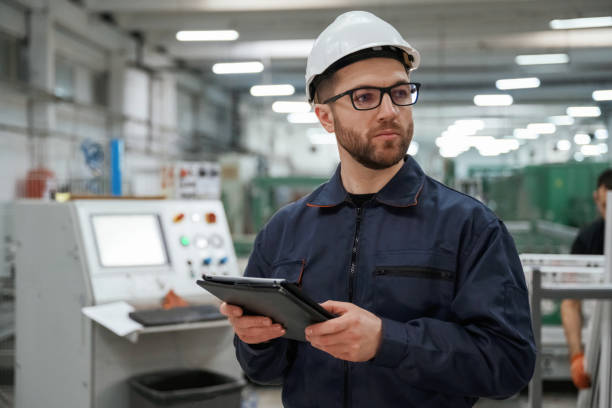 istock Holding tablet. Factory worker is indoors with hard hat 2147708750
