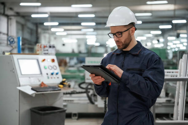 istock Holding tablet. Factory worker is indoors with hard hat 2147708761