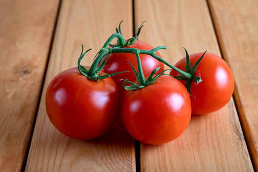 A group of red bunch tomatoes on a wooden table