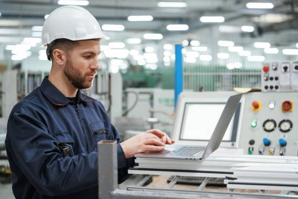 istock Using the laptop. Factory worker is indoors with hard hat 2147708803