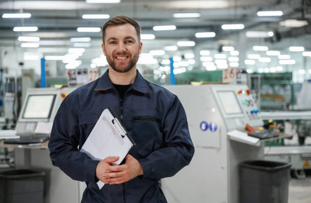 istock Standing and smiling. Factory worker is indoors with hard hat 2147708915