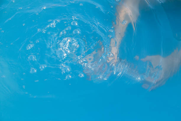 Woman's hands inside the pool with water filling water bottle due to drought