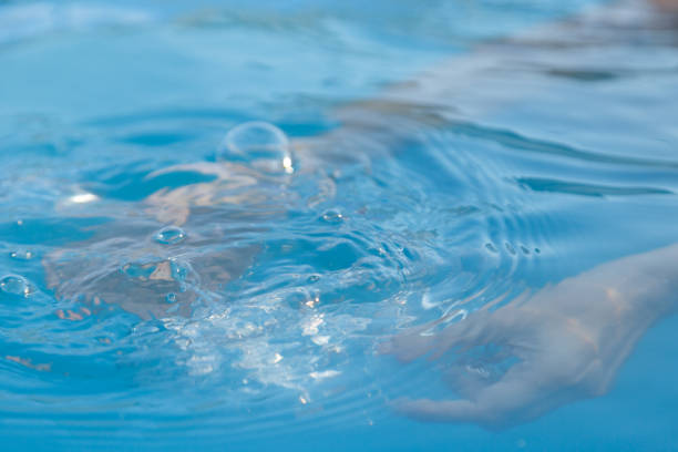 Woman's hands inside the pool with water filling water bottle due to drought