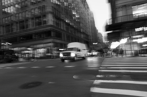 Street photography near Grand Central Station, New York City.  This is on a very wet and dark spring night with wet roads creating reflections of two yellow cabs at a cross roads.  Slow shutter speed creates movement blur for intentional camera movement and give a an abstract background.