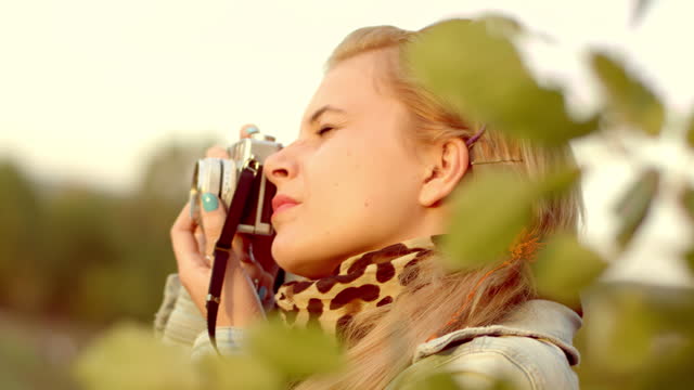 Woman taking photo pictures of nature with retro camera