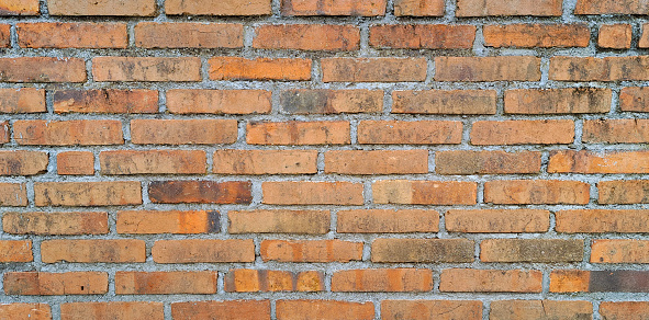 Exposed red brick wall texture on a rustic industrial building.