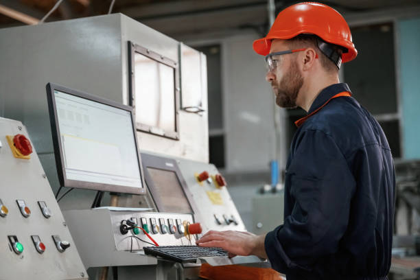 istock Operating the machine. Factory worker is indoors with hard hat 2147711344