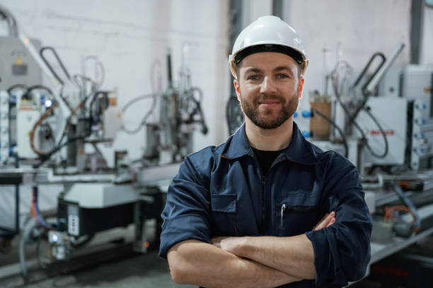 istock Front view. Factory worker is indoors with hard hat 2147711537