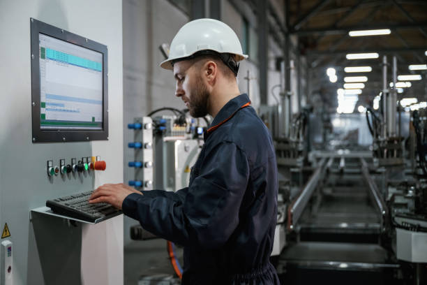 istock Adjusting settings of machine, operating. Factory worker is indoors with hard hat 2147711569