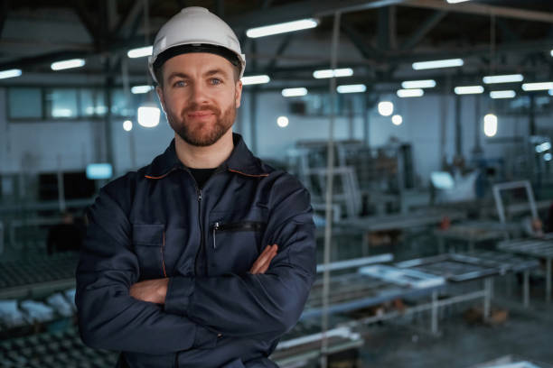istock Handsome friendly guy. Factory worker is indoors with hard hat 2147711574