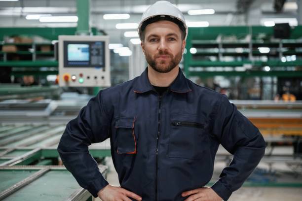 istock Against machine. Factory worker is indoors with hard hat 2147711869