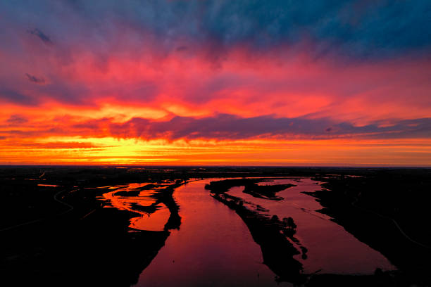 Amazing colorful sunset over the river IJssel in Overijssel, Netherlands during springtime seen from above. The strong colors in the sky are partly caused by the southern wind bringin sand from the Sahara desert over the European contintent.