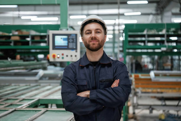istock Against machine. Factory worker is indoors with hard hat 2147711877