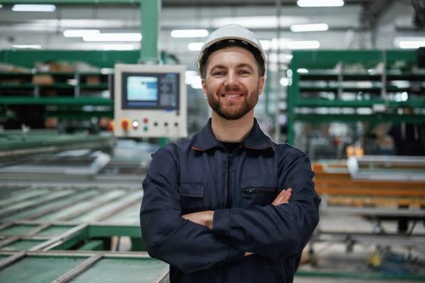 istock Against machine. Factory worker is indoors with hard hat 2147711888