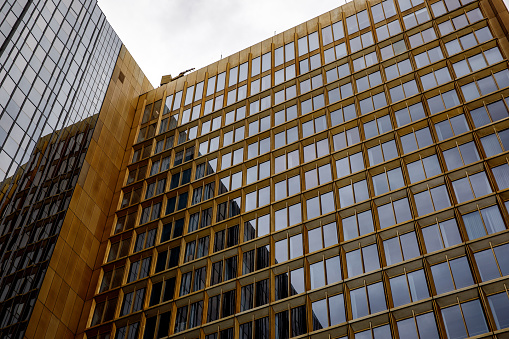 Golden-hued building adorned with reflective glass windows against a sleek, dark-toned structure.