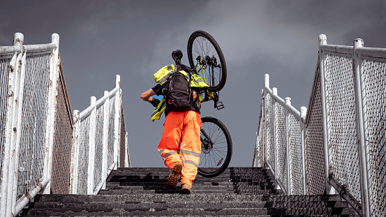 A man runs up a set of stairs  on his way to work carrying his bicycle