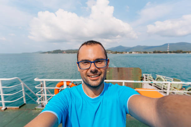 Handsome young man taking selfies on the ferry to Ko Phangan in Thailand.