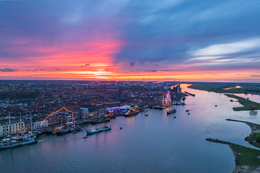 Kampen and river IJssel during the traditional fleet review or naval review at the start of the 2024 Sail Kampen event in the Hanseatic League city at the end of a springtime day with a colorful sunset in the sky.