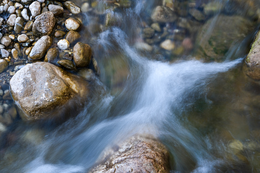 Low shutter speed stream shot. There is a stone in the middle of the water, Shot from the top angle