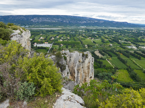 Photo of a breathtaking green panorama from the heights of the Alpilles with a view overlooking the Durance valley filled with fields and meadows. This photograph was taken in Provence in France.