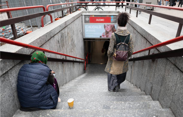 Milan, Italy - April 09, 2024: one woman is sitting on the stairs while the other is going down the subway