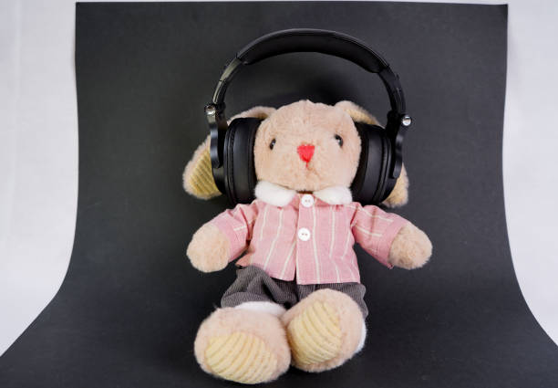 istock Toy brown plush rabbit on a black background with headphones 2147715708