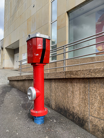 A red fire hydrant stands on the asphalt near a building in the German city of Pforzheim. Close-up. Vertical photo.