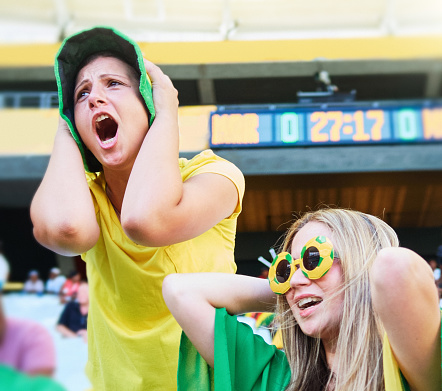 Oh no! Disappointed football supporters wearing green and yellow in an unidentifiable soccer stadium.