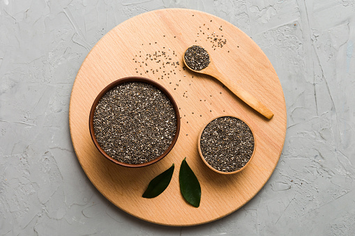 Chia seeds in bowl and spoon on colored background. Healthy Salvia hispanica in small bowl. Healthy superfood.