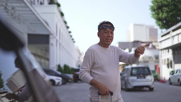 Senior Asian man waving at taxi