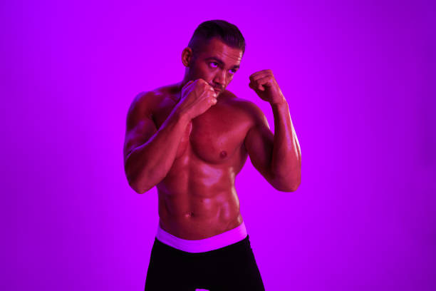 Man athletic bodybuilder poses with nude torso abs in full-length background, boxing and martial arts. Advertising, sports, active lifestyle, color light, competition, challenge concept. . High quality photo
