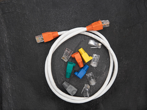 Local area network or LAN cable protector boots , RJ45 connectors and completed network cable isolated on dark background