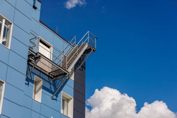 A blue office building wall with composite aluminum panels and a fire escape on the side.