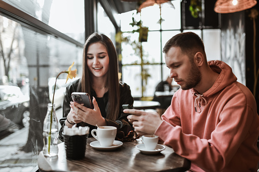 Couple Going Through Smartphones During Coffee Time