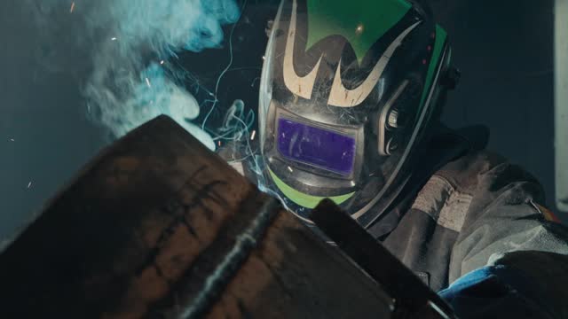 Male welder in a black jacket welds a metal object