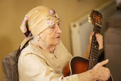 Music fills the air as a senior woman gracefully plays her guitar, lifting spirits in the nursing home.