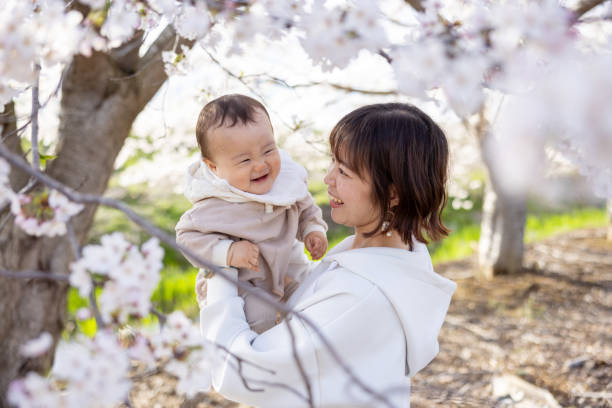 istock Mother holding her baby boy under cherry blossoms 2147867067