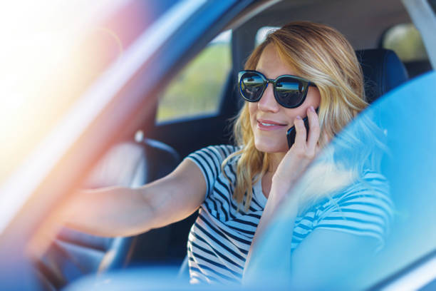 istock Beautiful woman using smartphone while driving car 2147942903