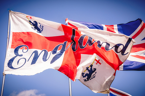 A flag featuring the St George's Cross, flying in the wind on a summer's day.