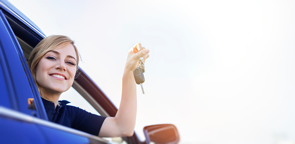 The woman driver shows the key to the car. Car purchase or rental.