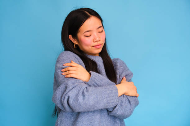 istock A woman in a blue sweater is hugging herself. 2148023049