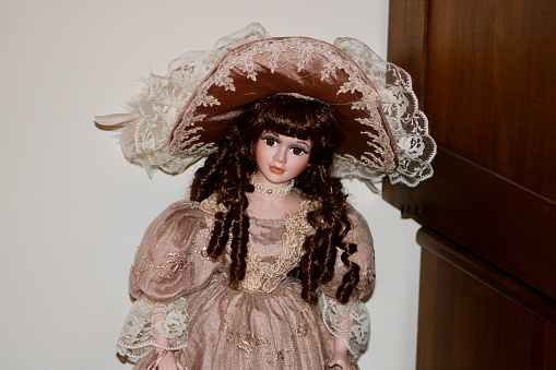 The close up view of a porcelain doll dressed in Victorian era clothing.