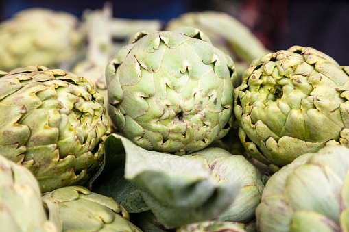 Artichokes hearts marinated with olive oil and herbs. Pickled artichoke with garlic in glass bowl on the table. Homemade healthy eating.